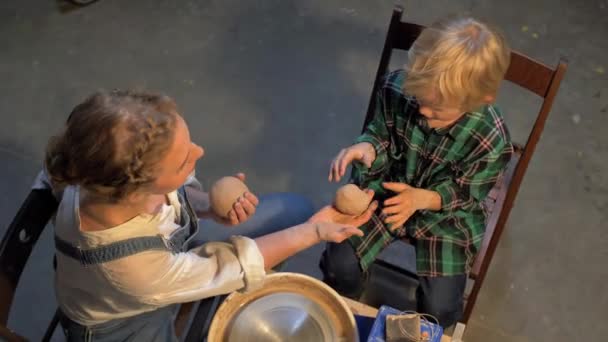 Vista dall'alto, donna con ragazzo preparare materiale per il lavoro sulla ruota della ceramica — Video Stock