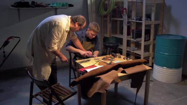 Mestre ajuda homem a fazer um sapato em uma oficina — Vídeo de Stock