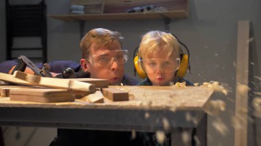 Erkek ve erkek masadaki ahşap talaşları yavaş çekimde uçurur.