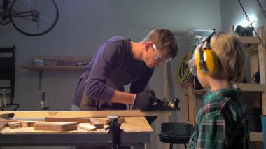 Çocuk, ustanın tahtayı nasıl cilaladığını izliyor. 