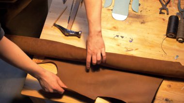 Adam atölyede kumaşı masanın üzerine boşaltıyor.