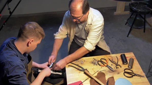 L'homme donne un outil à un maître dans un atelier de chaussures — Photo