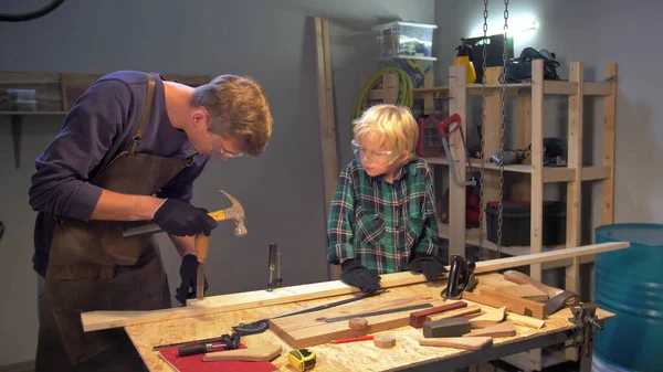 L'homme montre au garçon comment travailler le bois dans un atelier — Photo