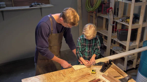 Ο άνθρωπος και το αγόρι εργάζονται με ξύλο σκάφους στο εργαστήριο — Φωτογραφία Αρχείου
