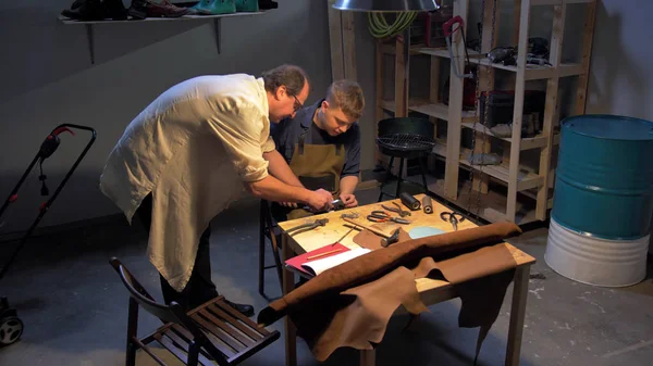 Master helps man to make a shoe in a workshop — Stock Photo, Image