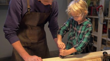 Çocuk atölyedeki tahtayı tamir ediyor.