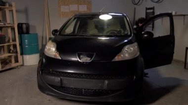 Bir adam arabanın kaputunun altında kontrol ediyor.