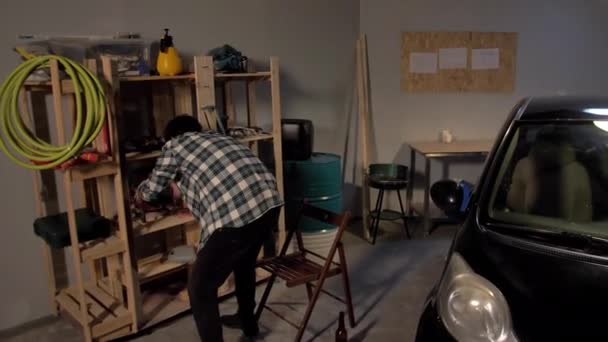 Guy inspeciona uma prateleira na garagem — Vídeo de Stock