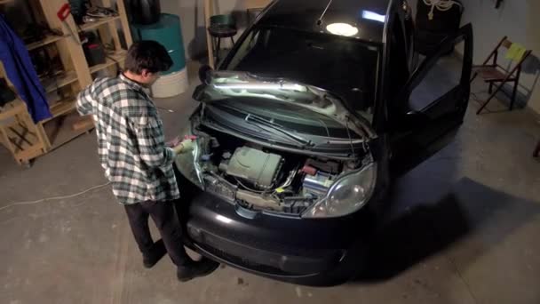 El hombre está reparando el motor del coche en el garaje — Vídeo de stock