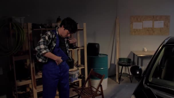 Человек-механик надевает униформу в гараже — стоковое видео