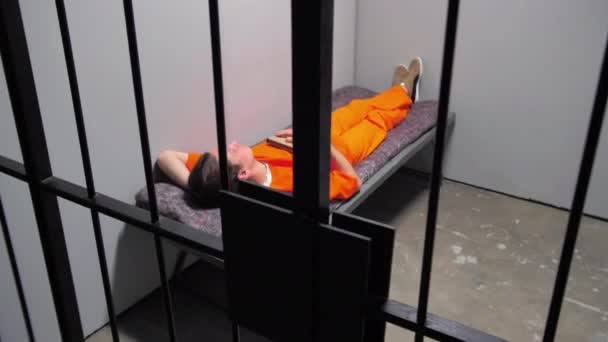 De crimineel slaapt op het bed achter de tralies — Stockvideo