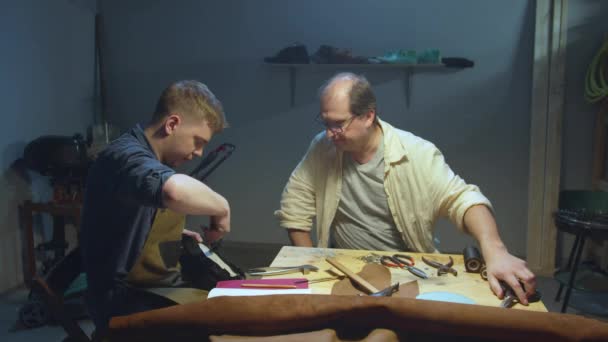 Master teaches apprentice how to work with skin — Stock Video
