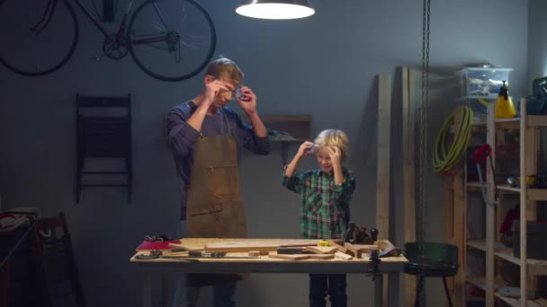 Padre e figlio indossano occhiali di sicurezza in officina — Video Stock