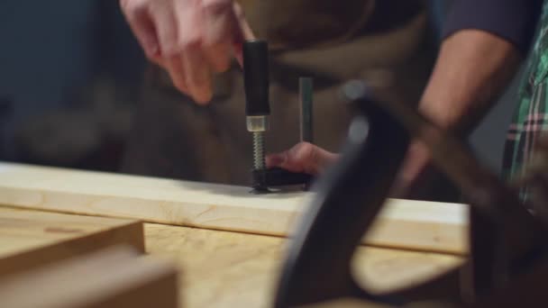 Der Tischler sichert die Stange mit einer Klemme — Stockvideo