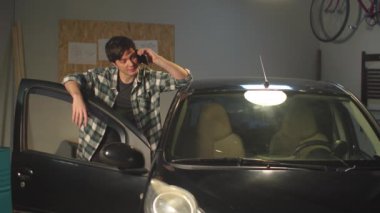 Adam kabaca telefonda konuşuyor ve arabanın kapısını çarpıyor.