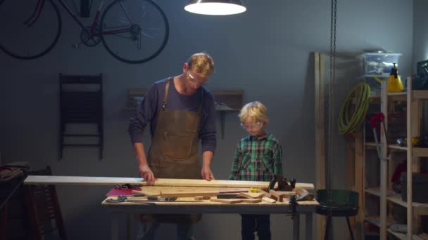 Отец учит сына работе плотника. — стоковое видео