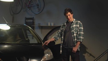 Bir adam arabasını gösteriyor.