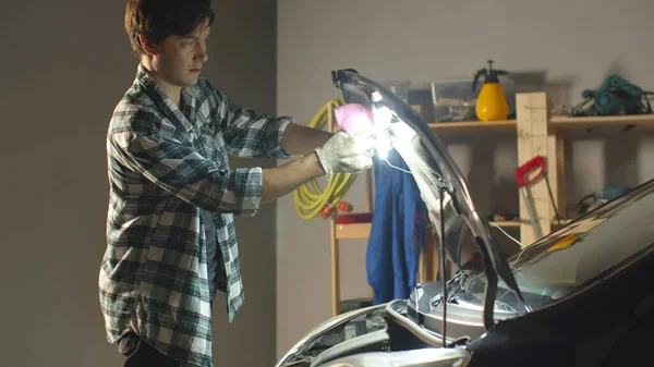 Mannen tar bort lampan och stänger motorhuven — Stockfoto