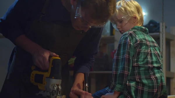 Papa et fils sciant une planche sur un établi — Photo