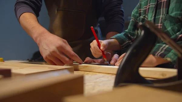 Jongen met potlood maakt reeksen op een houten plank. Garagewerkplaats — Stockfoto
