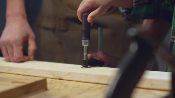 De jongen probeert een houten plank in een bankschroef te klemmen. — Stockvideo