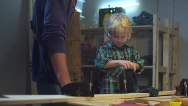 Tata pomaga synowi nosić rękawice ochronne do pracy w garażu — Wideo stockowe