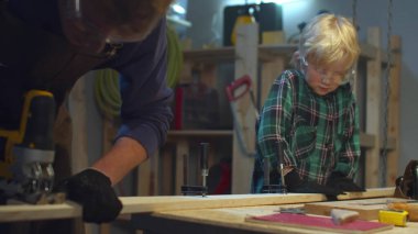 Çocuk babamın tahta kesmesine yardım ediyor. Kaydırma