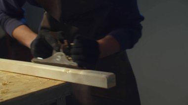 Atölyede bir adam bir parça odun kesiyor. Kaydırma 