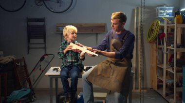 Baba oğlunun oyuncağını tamir eder. Orta uzunlukta.