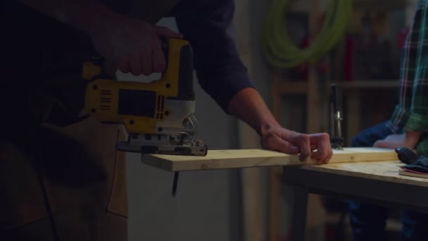 Un hombre está aserrando una tabla con un rompecabezas — Vídeo de stock