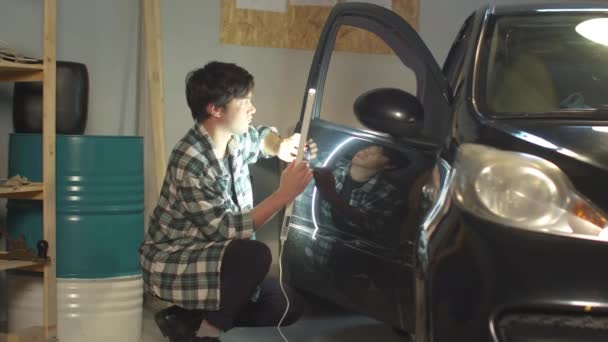 Mechanic inspects car door with ultraviolet lamp — Stock Video