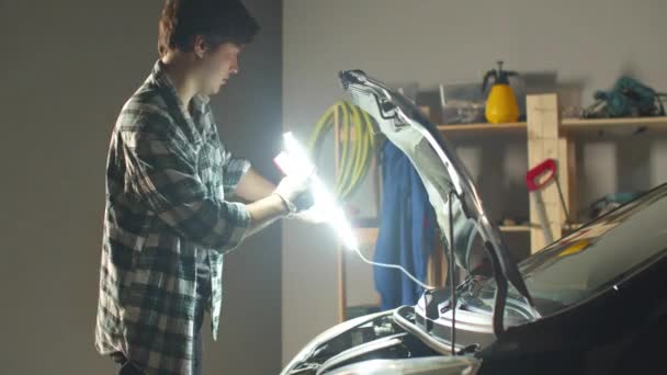 Mannen tar bort lampan och stänger motorhuven — Stockvideo