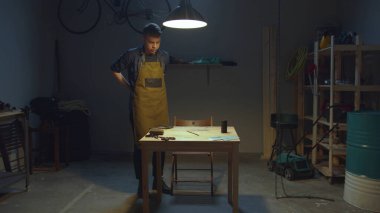 Zanaatkar atölyeye girer ve önlüğünü giyer.