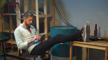 Adam dinleniyor ve telefonla haberleri izliyor.