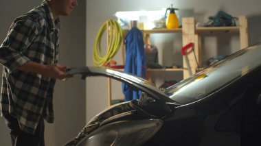 Şoför garajda arabadan indi ve kaputu kaldırdı.