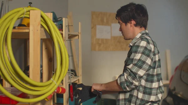 Le gars met des gants pour ranger dans le garage — Photo