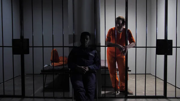 Prisoner speaks with security guard through bars — Stock Photo, Image