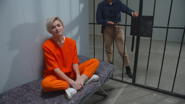 Suçlu, bir gardiyanın gözetiminde hücrede oturuyor.