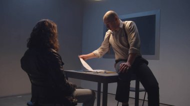 Bir dedektif, bir adama bir manyağın kurbanlarının fotoğrafını gösterir.