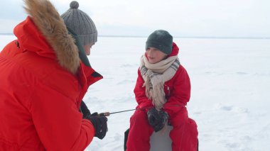 Baba oğluna oltayı nasıl kullanacağını anlatıyor.