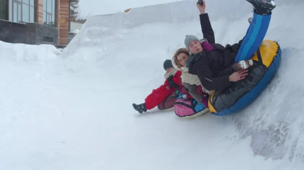 Maman papa et les enfants montent un tube en hiver — Photo