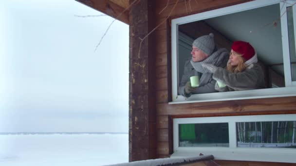 Par tittar ut genom fönstret och dricker kaffe — Stockvideo