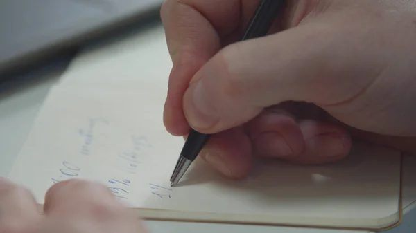 Un homme écrit avec un stylo dans un carnet. Gros plan — Photo