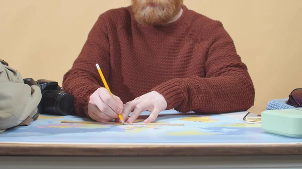 Бородач в свитере рисует на карте — стоковое фото