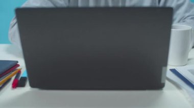 Ofis çalışanı bir dizüstü bilgisayar açar ve belgelerle çalışır.