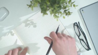 Bir adam deftere yazar. Üst görünüm