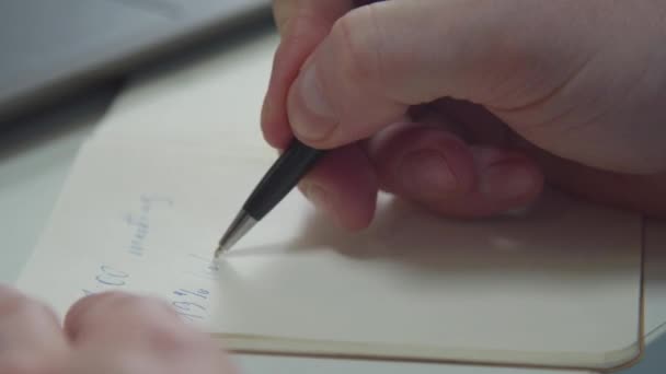 Een man schrijft met een pen in een notitieboekje. Close-up — Stockvideo