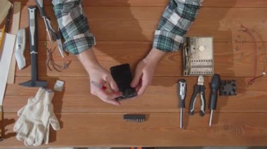 Tamirci bozuk bir telefon ekranını inceliyor.