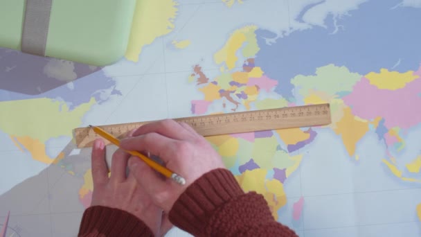 Um homem traça uma linha em um mapa e escreve em um caderno — Vídeo de Stock