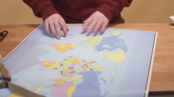 Ein Mann rollt eine Landkarte und holt Papier und Stift heraus — Stockvideo